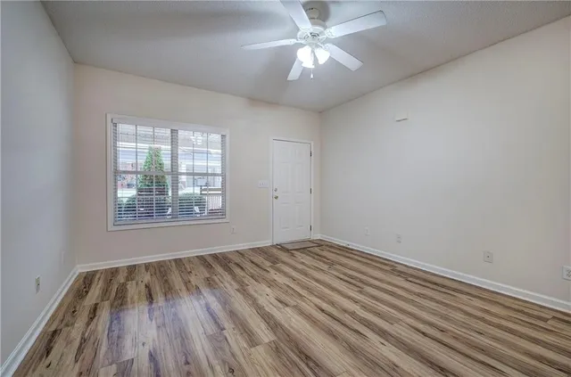 a view of an empty room with wooden floor and a window