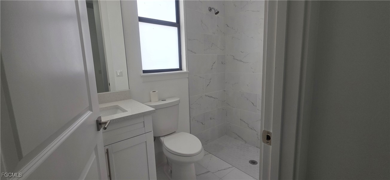 925 Chenault Street Lehigh Acres, FL 33974 - Photo 14 of 16 a bathroom with a granite countertop toilet and a sink