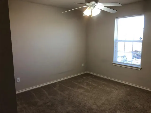 an empty room with a chandelier fan and windows