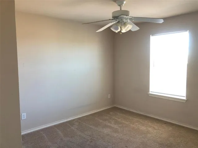 an empty room with a window and a fan