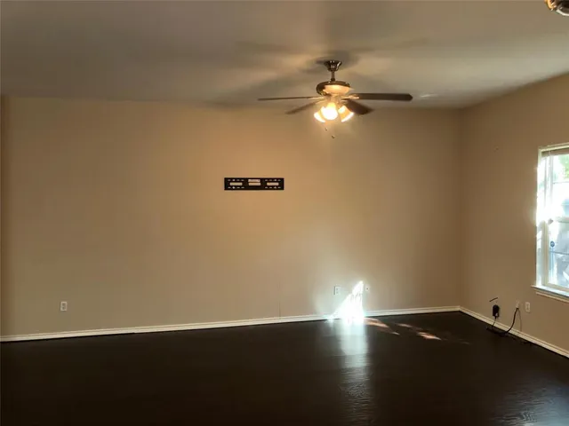 a view of an empty room with window and wooden floor