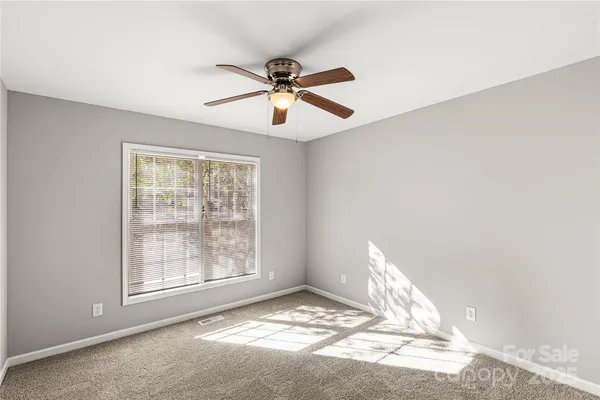 an empty room with closet and a chandelier fan