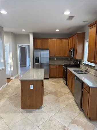 a large kitchen with stainless steel appliances granite countertop a stove a sink and a refrigerator