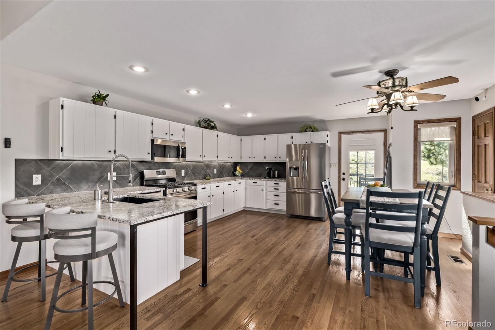 a kitchen with stainless steel appliances kitchen island granite countertop a table chairs and a refrigerator