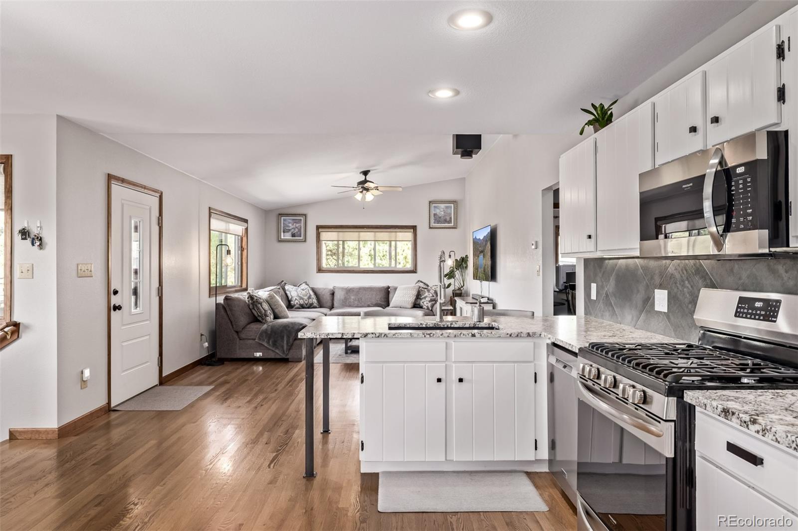 13950 Pine Valley Road Pine, CO 80470 - Photo 11 of 49 a kitchen with stainless steel appliances a stove a sink dishwasher a refrigerator white cabinets and wooden floor