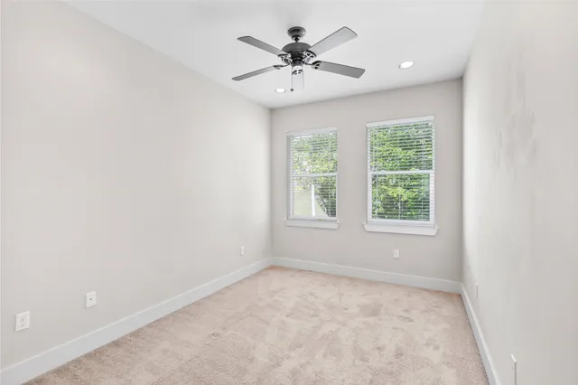 an empty room with a window and a chandelier fan