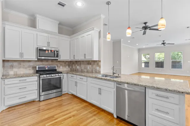 a kitchen with granite countertop a stove a sink and dishwasher wooden cabinets with wooden floor