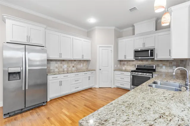 a kitchen with granite countertop a refrigerator stove and microwave