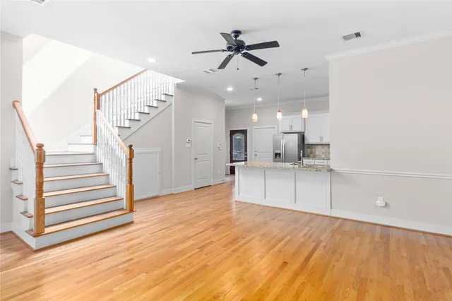 a view of an empty room with wooden floor and a ceiling fan