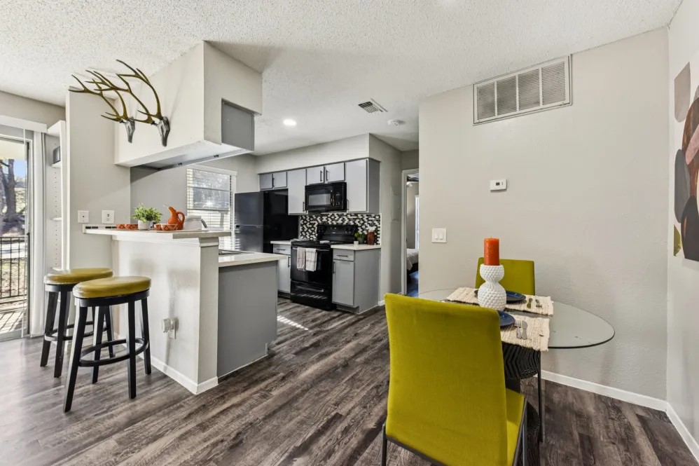 2501 Wickersham Lane, Unit 1033 Austin, TX 78741 - Photo 9 of 12 a kitchen with stainless steel appliances granite countertop a refrigerator a stove top oven a sink dishwasher and white cabinets with wooden floor