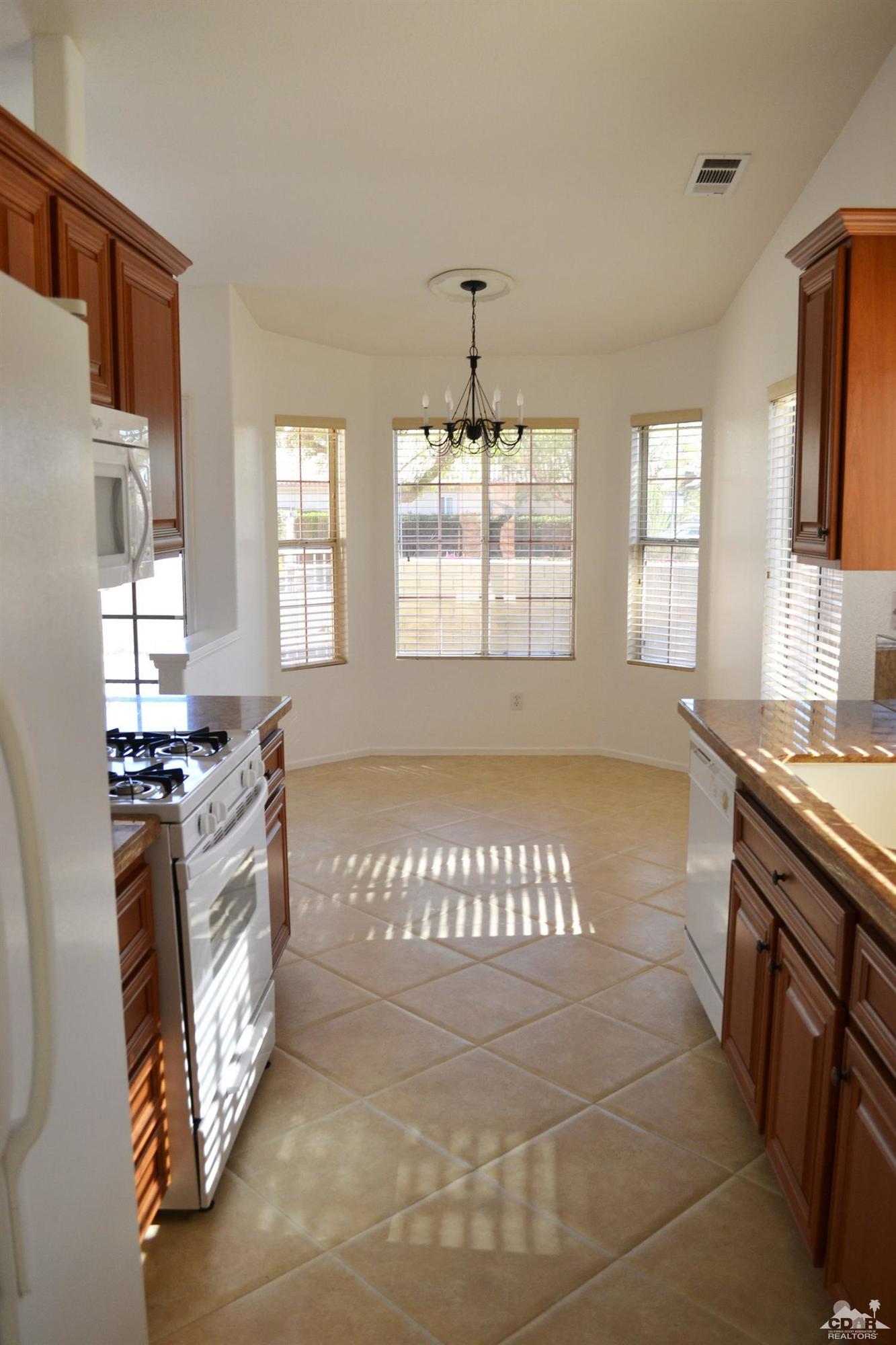 49699 Truman Way Indio, CA 92201 - Photo 7 of 19 a large kitchen with granite countertop a stove top oven a sink and a window