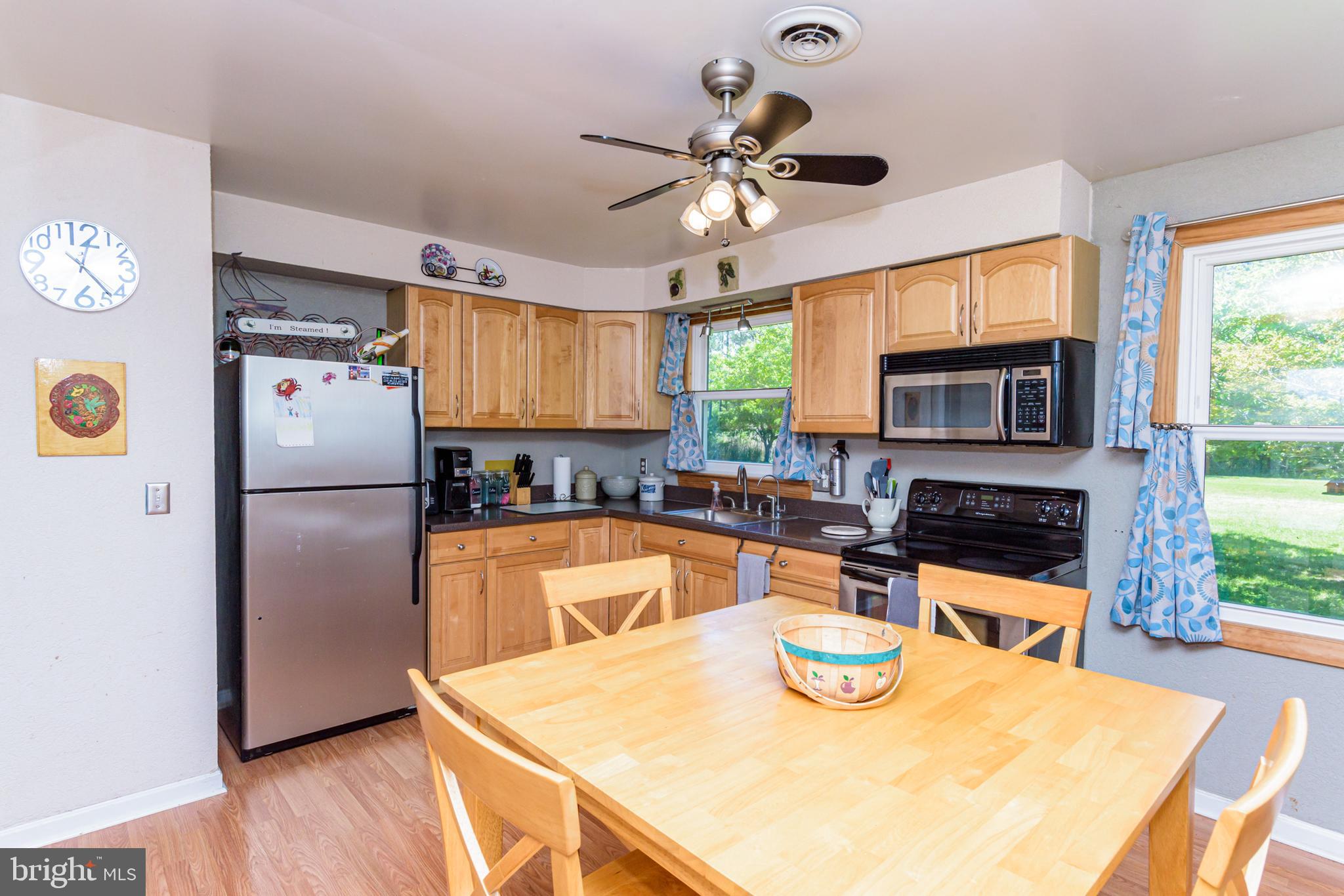 23212 Haines Point Road Chance, MD 21821 - Photo 33 of 57 a kitchen with stainless steel appliances granite countertop a refrigerator a stove a sink a dining table and chairs with wooden floor