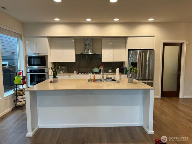 a large kitchen with stainless steel appliances a large counter top a stove and a refrigerator