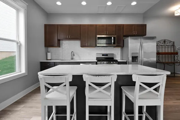 a kitchen with stainless steel appliances granite countertop a sink a microwave a refrigerator and cabinets