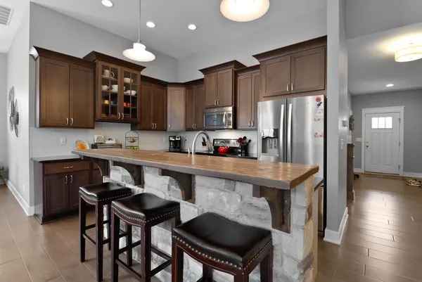 a kitchen with stainless steel appliances a table chairs refrigerator and microwave