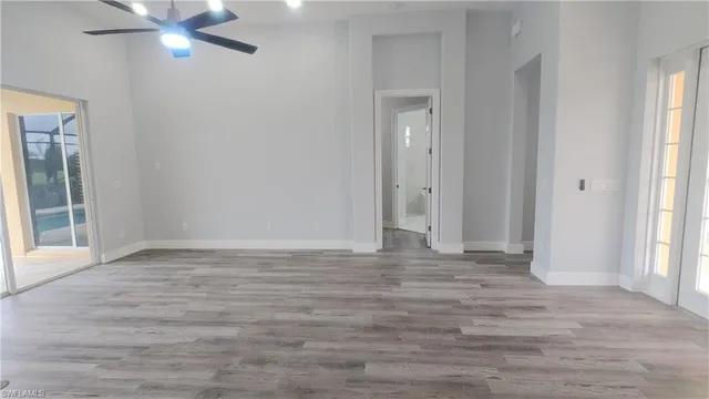 a view of an empty room with wooden floor and a window