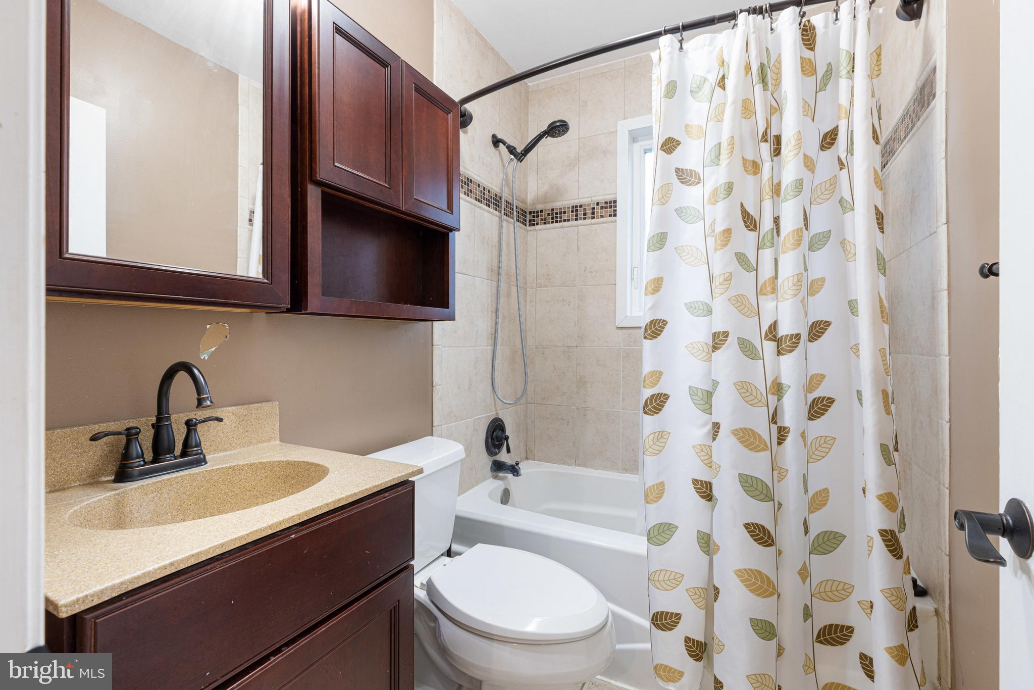 422 Elmwood Road Baltimore, MD 21206 - Photo 16 of 29 a bathroom with a sink toilet a mirror and shower curtain
