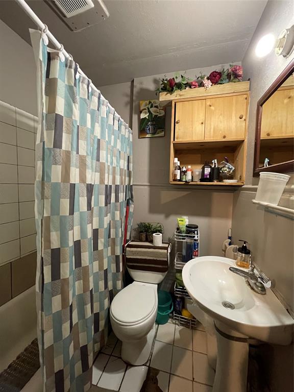 607 Neches Street Dallas, TX 75208 - Photo 6 of 12 a bathroom with a sink a toilet and shower curtain