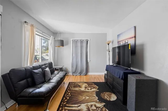 a living room with furniture a flat screen tv and a refrigerator