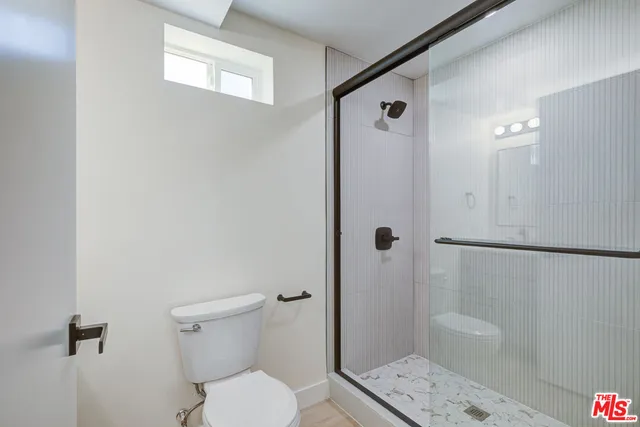 a bathroom with a granite countertop sink a toilet and shower