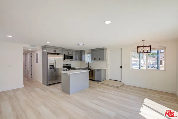 a living room with stainless steel appliances kitchen island granite countertop a stove and a refrigerator