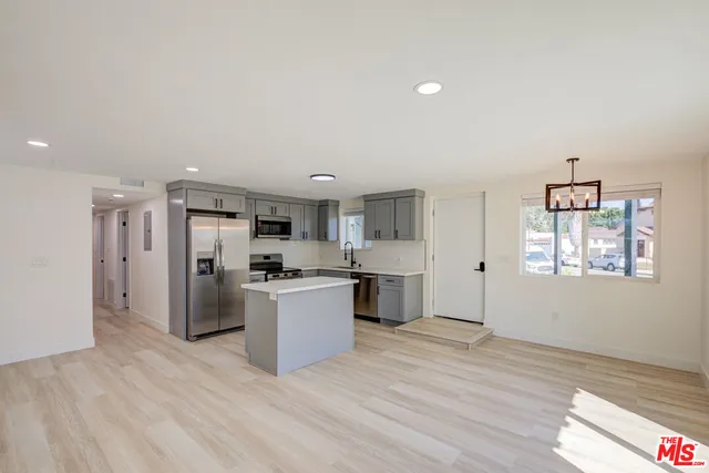 a living room with stainless steel appliances kitchen island granite countertop a stove and a refrigerator