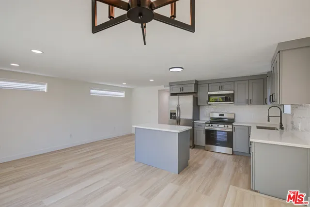 a kitchen with kitchen island a stove a sink and a refrigerator