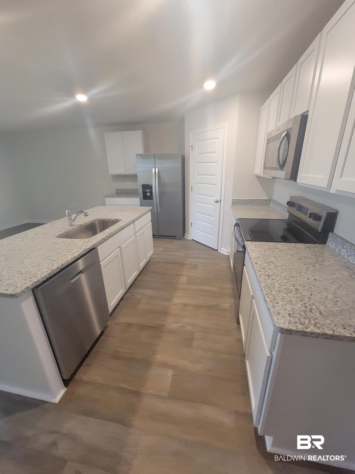 24625 Ponder Loop Loxley, AL 36551 - Photo 25 of 30 Kitchen with white cabinetry, hardwood / wood-style floors, stainless steel appliances, and a center island with sink