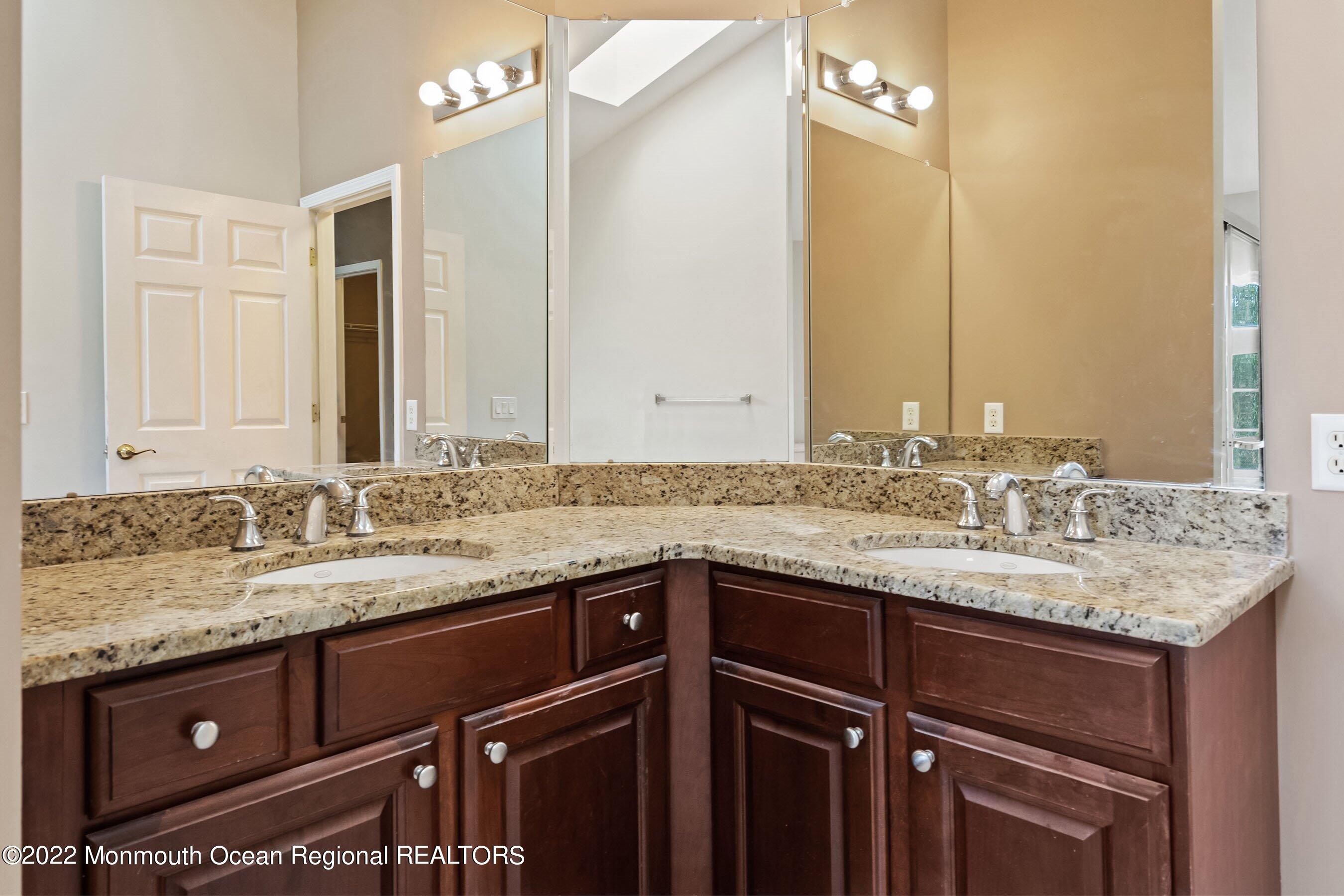 107 Bryce Lane, Unit 2004 Manahawkin, NJ 08050 - Photo 21 of 39 a bathroom with a granite countertop sink and a mirror