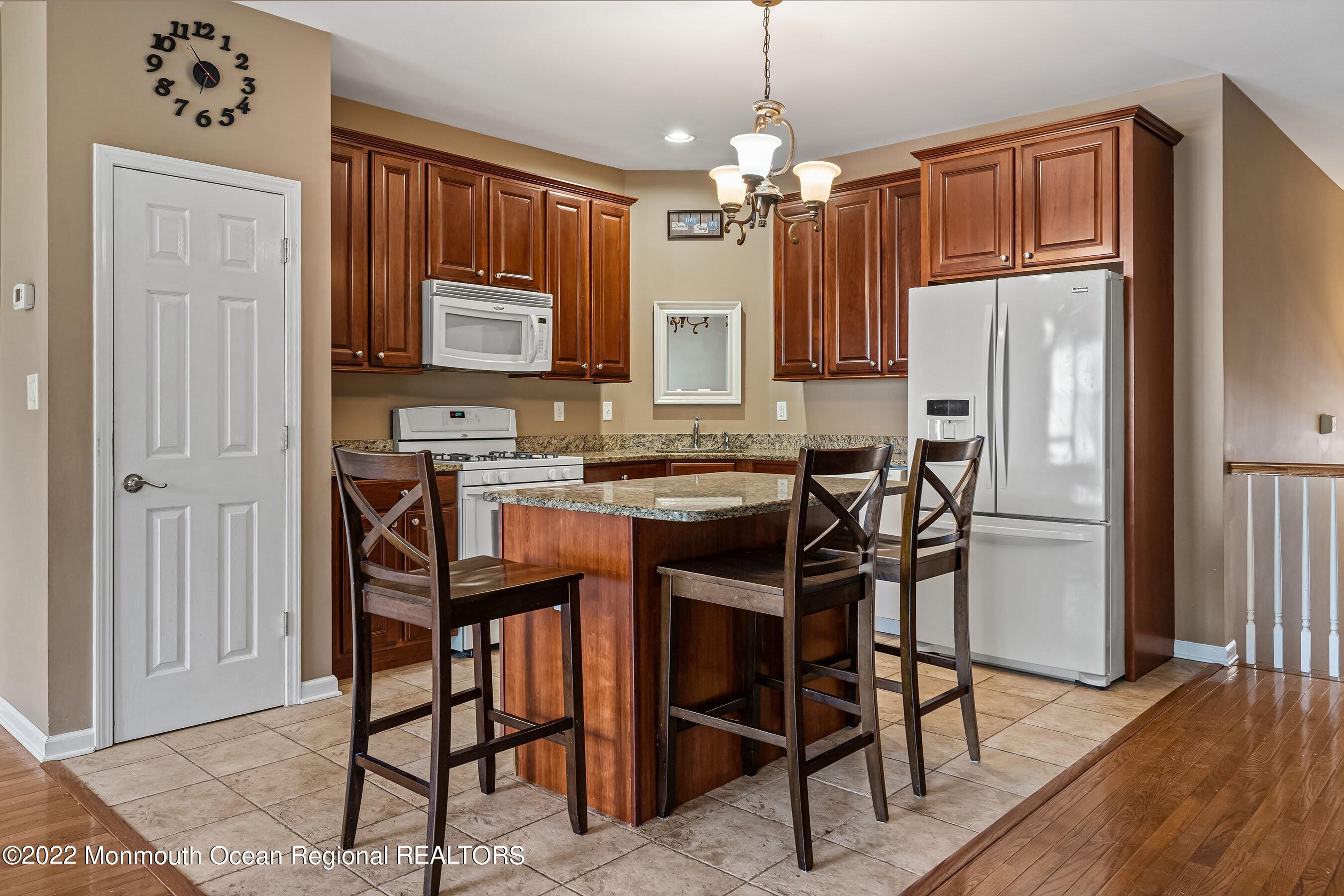 107 Bryce Lane, Unit 2004 Manahawkin, NJ 08050 - Photo 9 of 39 a kitchen with stainless steel appliances granite countertop a refrigerator a stove a sink a dining table and chairs with wooden floor