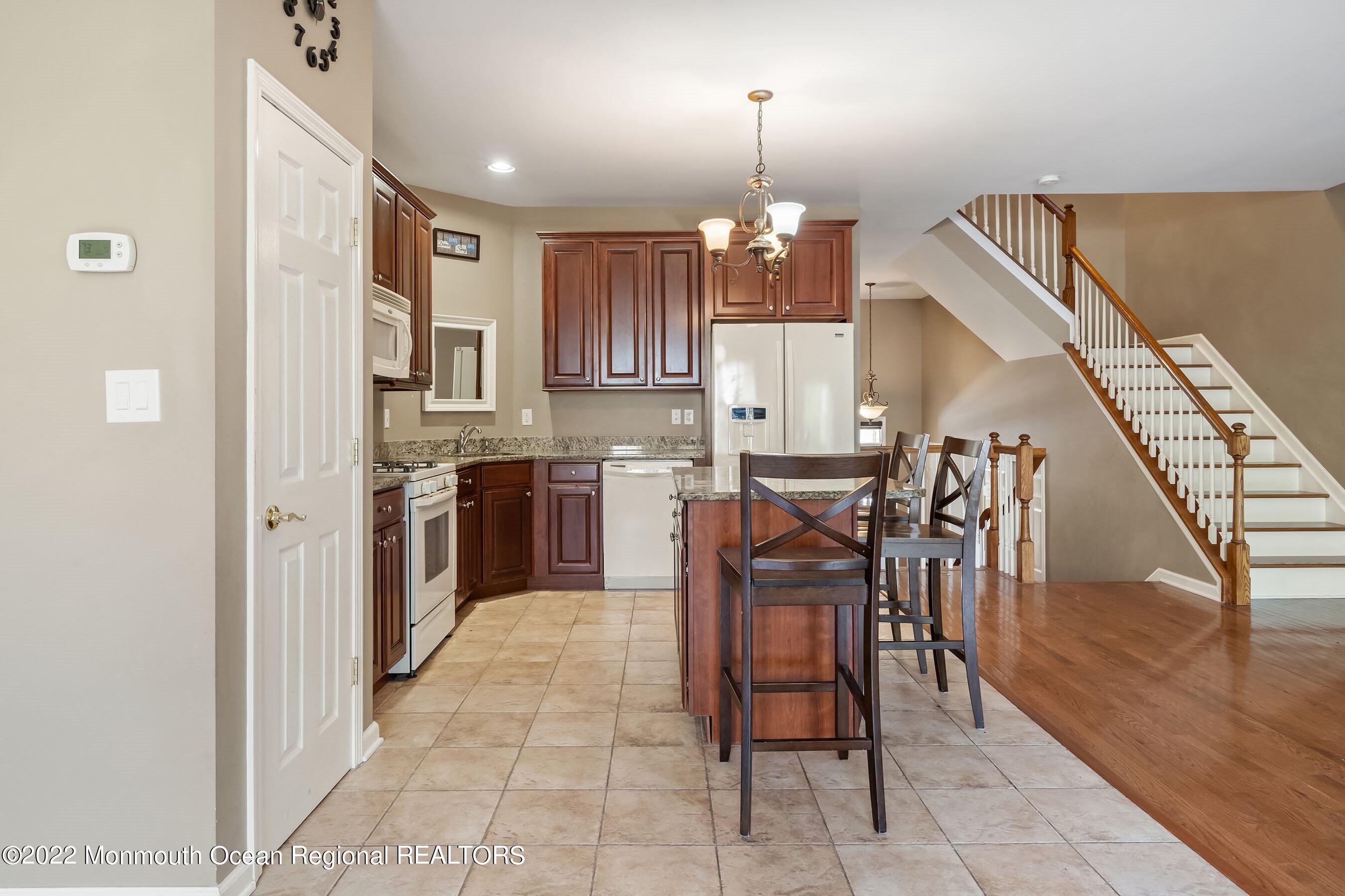 107 Bryce Lane, Unit 2004 Manahawkin, NJ 08050 - Photo 10 of 39 a open kitchen with stainless steel appliances kitchen island granite countertop a table chairs and a refrigerator
