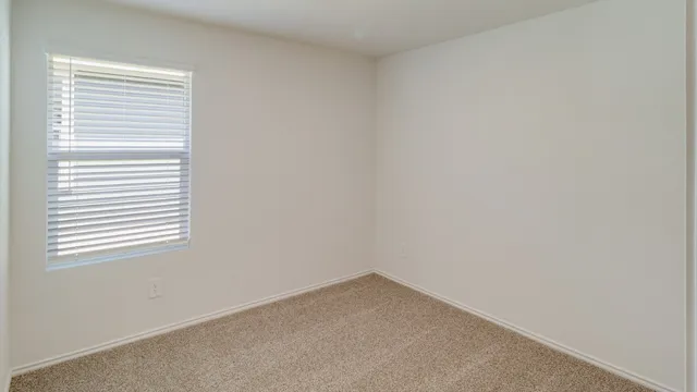 a view of an empty room with closet and a window