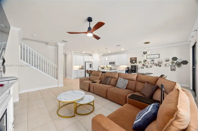 a living room with furniture kitchen view and a chandelier
