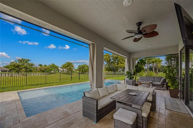 a view of a backyard with couches plants and large trees