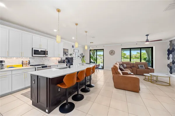 a living room with stainless steel appliances furniture and a kitchen view
