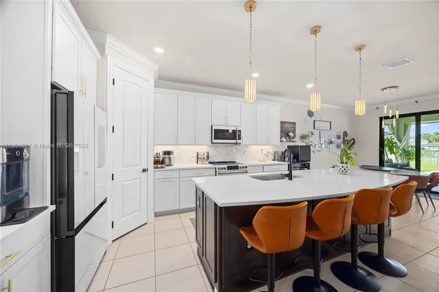 a large kitchen with kitchen island granite countertop lots of white cabinets appliances and furniture