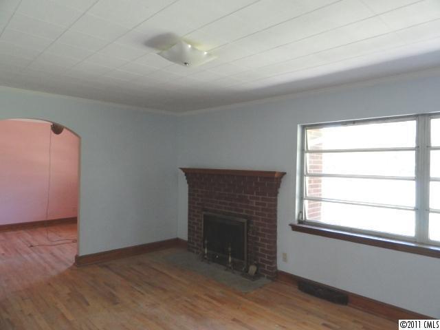 1300 Shearers Road Mooresville, NC 28115 - Photo 4 of 7 an empty room with wooden floor a fireplace and windows