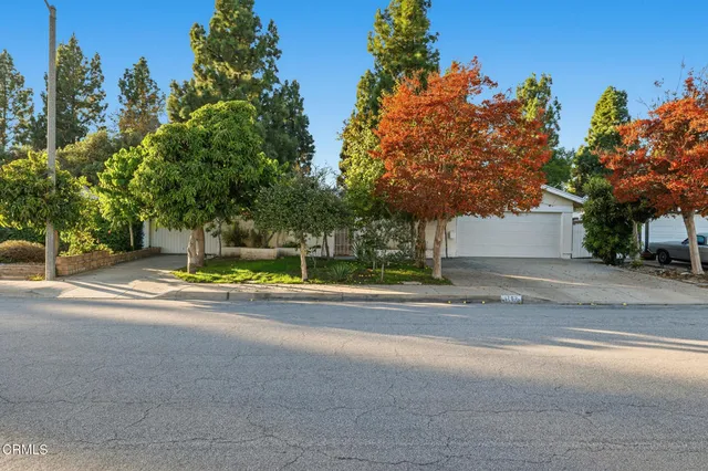 a view of a house with a road and trees