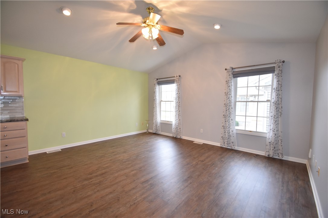 603 South Raccoon Road, Unit 49 Youngstown, OH 44515 - Photo 11 of 27 Empty room featuring visible vents, baseboards, ceiling fan, dark wood-style flooring, and vaulted ceiling