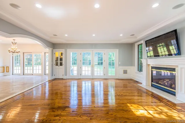a big room with wooden floor fire place and windows