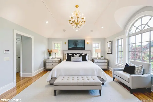 a spacious bedroom with a bed a chandelier and a large window with outer view
