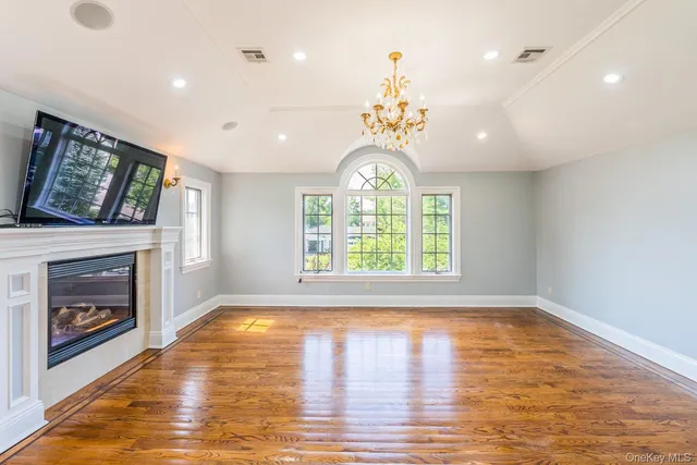 a view of an empty room with wooden floor fireplace and a window