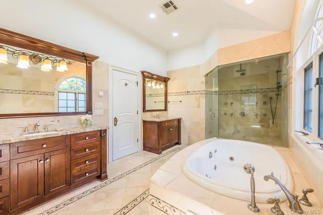 a bathroom with a tub a sink a mirror and a shower