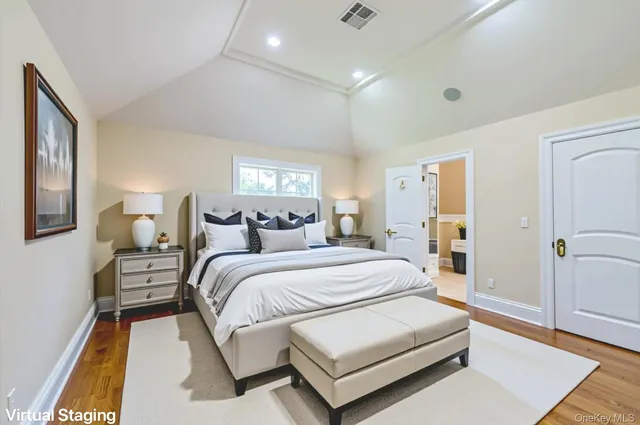 a spacious bedroom with a bed and wooden floor