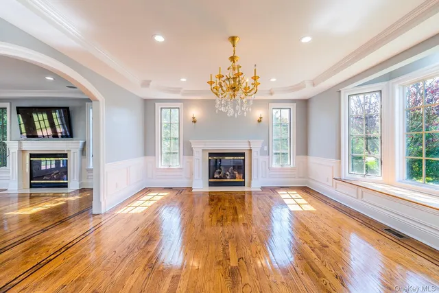 a view of an empty room with wooden floor fireplace and a window