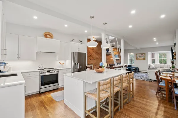 a kitchen with stainless steel appliances kitchen island granite countertop a stove a sink a refrigerator and chairs