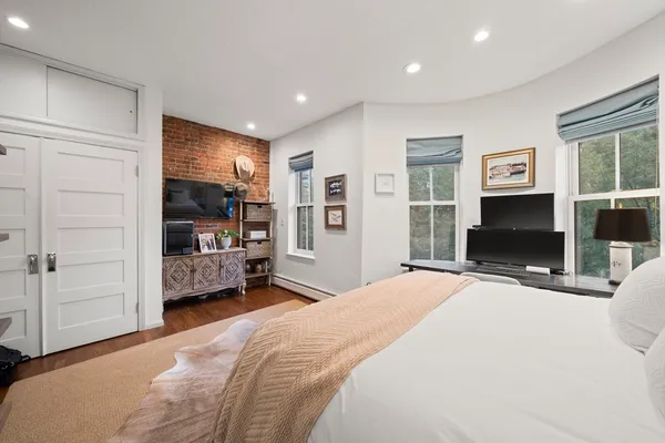 a bedroom with a bed a flat screen tv and dresser