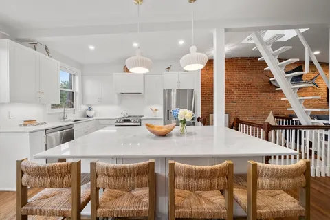 a kitchen with stainless steel appliances kitchen island granite countertop a sink and a white cabinets