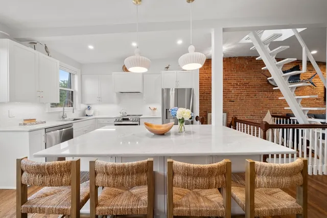 a kitchen with stainless steel appliances kitchen island granite countertop a sink and a white cabinets