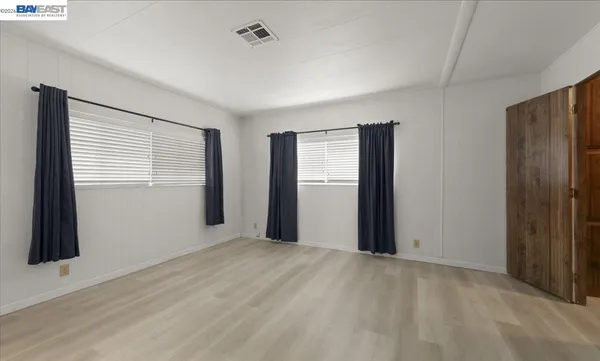 a view of an empty room with closet and a window